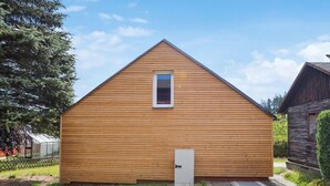 Una pequeña construcción de madera con techo triangular, una puerta y un ventanal.