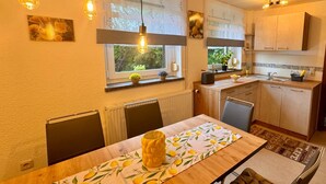 Uma cozinha moderna com armários de madeira, uma mesa de jantar com toalha de mesa estampada com limões e luminárias pendentes.