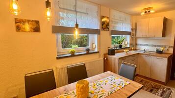Eine moderne Küche mit Holzausziehtischen, einem Esstisch mit Tischdecke mit Zitronenmuster und Pendelleuchten.
