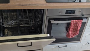Eine Küche mit Geschirrspüler, Backofen und einem an dem Backofen angehängten, rot karierten Handtuch.