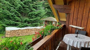 A balcony with a wooden railing, a table with a floral tablecloth, and a chair. - Seitz 1 in Bayerisch Eisenstein by Interhome (Bayerisch Eisenstein)