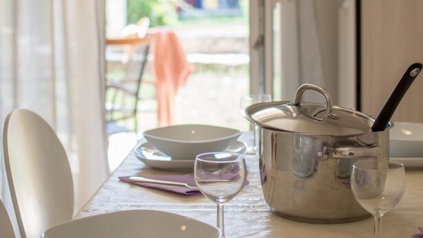 Une table à manger avec un pot, deux verres à vin et un bol.