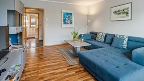A modern living room with a blue sofa, a coffee table, and a wooden floor. There is a door leading to another room and a framed picture on the wall. - mit Balkon und schönem Moselblick by Interhome (Klüsserath)