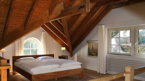A bedroom with a wooden ceiling, a bed, a window with a view of trees, and a painting on the wall. - Fachwerkhaus mit Garten, Grill und Terrasse by Interhome (Blankenheim)
