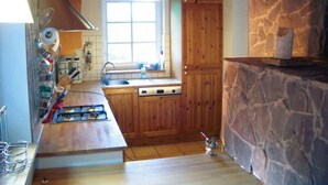 A kitchen with wooden cabinets, a stone wall, a window, and a hanging light fixture. - Fachwerkhaus mit Garten, Grill und Terrasse by Interhome (Blankenheim)