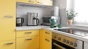 A modern kitchen with yellow cabinets, a stainless steel coffee maker, a microwave, and a green teapot. - Großzügige Wohnung mit Bergblick im Haus Hopfe by Interhome (Goslar)