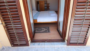 Une chambre à coucher avec un lit, des volets en bois et un petit tapis.