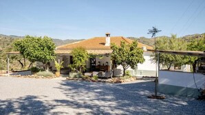 A house with a tiled roof, surrounded by gravel and trees, set against a hilly landscape. - 5-Bedroom Villa with Pool, Swimjet and Jacuzzi (Comares)