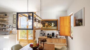 A modern kitchen with wooden cabinets, a dining table with fruit, and a hanging light fixture. - 5-Bedroom Villa with Pool, Swimjet and Jacuzzi (Comares)