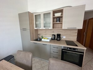 Een koelkast, een oven, kookgerei, borden en bestek