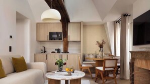 Una sala de estar moderna con un sofá, una mesa de centro, un comedor con mesa y sillas, una cocina con armarios de madera y un microondas, y una chimenea.