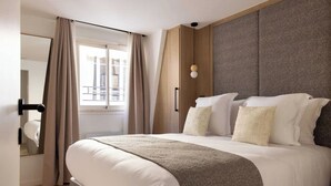 Una habitación de hotel moderna con una cama grande, un armario y una ventana con cortinas.