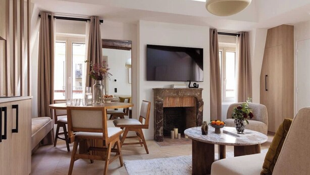 Una sala de estar moderna con chimenea, comedor y televisor montado en la pared.