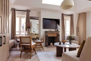 Ein modernes Wohnzimmer mit Kamin, Essbereich und Wand-Fernseher.
