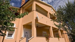 Un edificio de dos pisos con fachada color crema, una chimenea visible y un balcón.