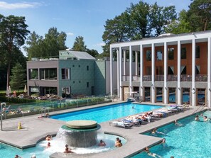 Ein modernes Hotel mit großem Außenpool, Liegebereichen und einem Wasserfall.