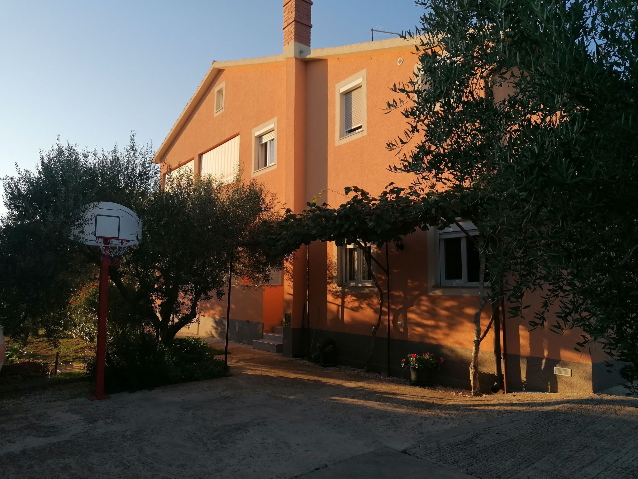 A residential building with a basketball hoop in the foreground.