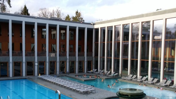 Un hotel con una amplia zona de piscina al aire libre, múltiples piscinas y tumbonas.