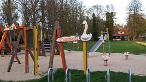 Un parque infantil con un módulo de juegos con temática de cisne, que incluye un tobogán y columpios.