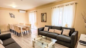 A living room with a sofa, a glass coffee table, a dining table with chairs, and a large window with curtains. - Villa Ana by Interhome (Rovinj)