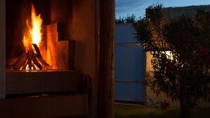 A fireplace with a visible fire, a wooden structure, and a blue building in the background. - Villa Ana by Interhome (Rovinj)