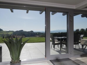 Eine moderne Terrassenanlage mit Glastür und Blick auf sanfte Hügel und Berge.