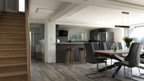 Una cocina moderna con una isla central, suelo de madera y un comedor con taburetes de bar.