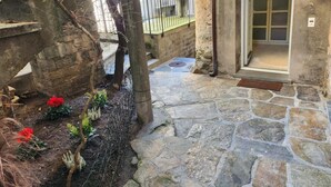 A stone-paved courtyard with a stone wall, a wooden door, and a metal gate. - Haus Antonini by Interhome (Brissago)