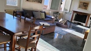 A spacious living area with a dining table, sofas, and a fireplace. - Haus Antonini by Interhome (Brissago)