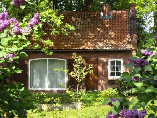 Ein Ziegelhaus mit einem Ziegeldach, einem großen Fenster und einer Tür.