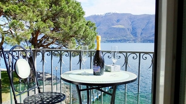 A balcony with a round table, a bottle of champagne, and a glass. - See-Penthouse by Interhome (Brissago)