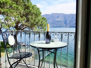 Un balcon avec une table ronde, une bouteille de champagne et un verre.