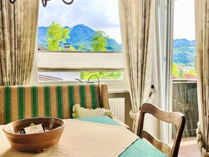 A room with a bed, a wooden chair, a window with a view of mountains, and a bowl on the table. - Wohnung in Bergen und Panoramablick by Interhome (Bergen)