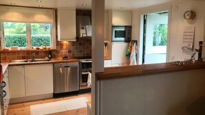 A modern kitchen with stainless steel appliances, a window with a view of greenery, and a clock on the wall. - "Torekov" mit Blick auf das Wasser by Interhome (Torekov)