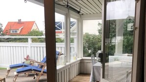 A covered porch with wooden flooring, a table, and blue lounge chairs. - "Torekov" mit Blick auf das Wasser by Interhome (Torekov)