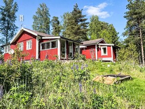 A red wooden house with a porch, surrounded by lush greenery and tall trees. - Idyllisch gelegenes, ebenerdiges Haus mit Terrasse by Interhome (Svenljunga)
