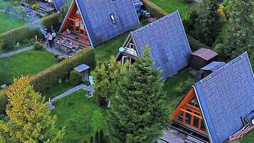 Eine Gruppe von A-Chalets mit geneigten Dächern, umgeben von gepflegten Rasenflächen und Bäumen.