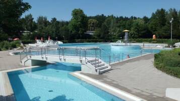 Ein Schwimmbecken mit Sprungturm und Stufen zum Wasser.