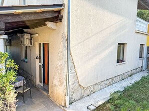 Ein Gebäude mit steinernen Fundament, einer Tür mit Vorhang und einem kleinen Fenster.