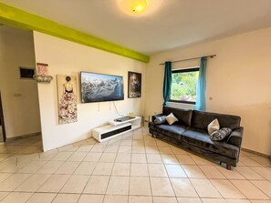 Ein Wohnzimmer mit Flachbildfernseher, einer Couch, einem Couchtisch und Kunstwerken an den Wänden.
