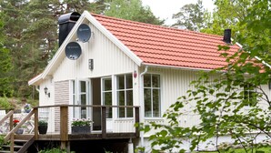 Un bâtiment blanc avec un toit rouge, une terrasse en bois et des antennes paraboliques.