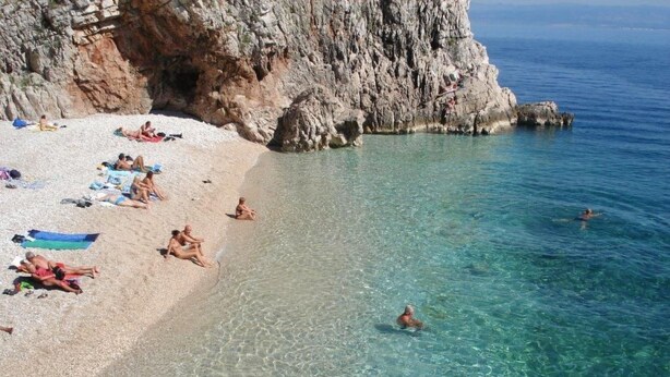 A beach with clear water, rocky cliffs, and people sunbathing and swimming. - Geräumiges Ferienhaus in Brseč mit Privatem Pool by Interhome (Brseč)