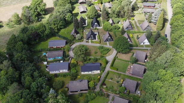 Luchtbeeld van een woongebied met huizen, groenstroken en een zwembad.