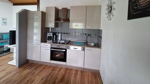 Una cuina moderna amb armaris blancs, forn integrat i cafetera.