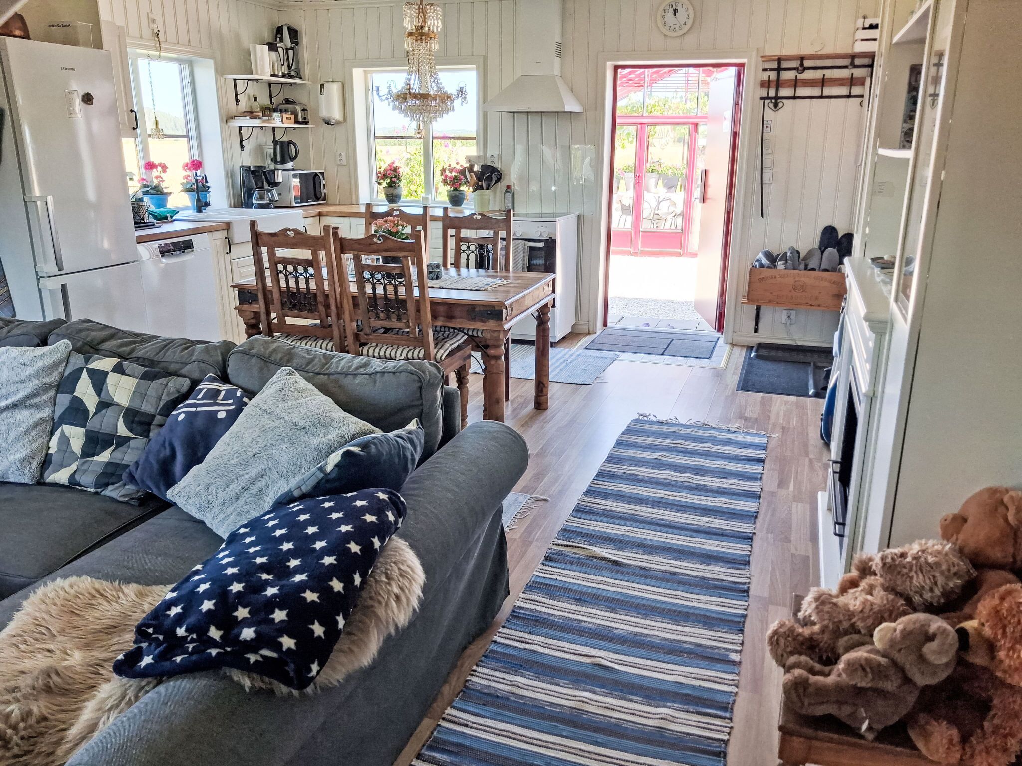A cozy living room with a sofa, a dining area with a table and chairs, a kitchen with appliances, and a view of the outdoors.