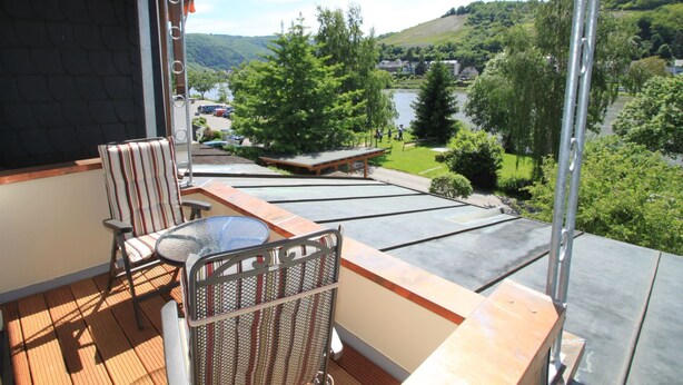 A balcony with a table and chairs, overlooking a scenic view of a lake and hills. - Simonis Privatpool by Interhome (Zell (Mosel))