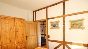 A bedroom with a bed, wooden wardrobe, and a white wall with wooden beams. - Simonis Privatpool by Interhome (Zell (Mosel))