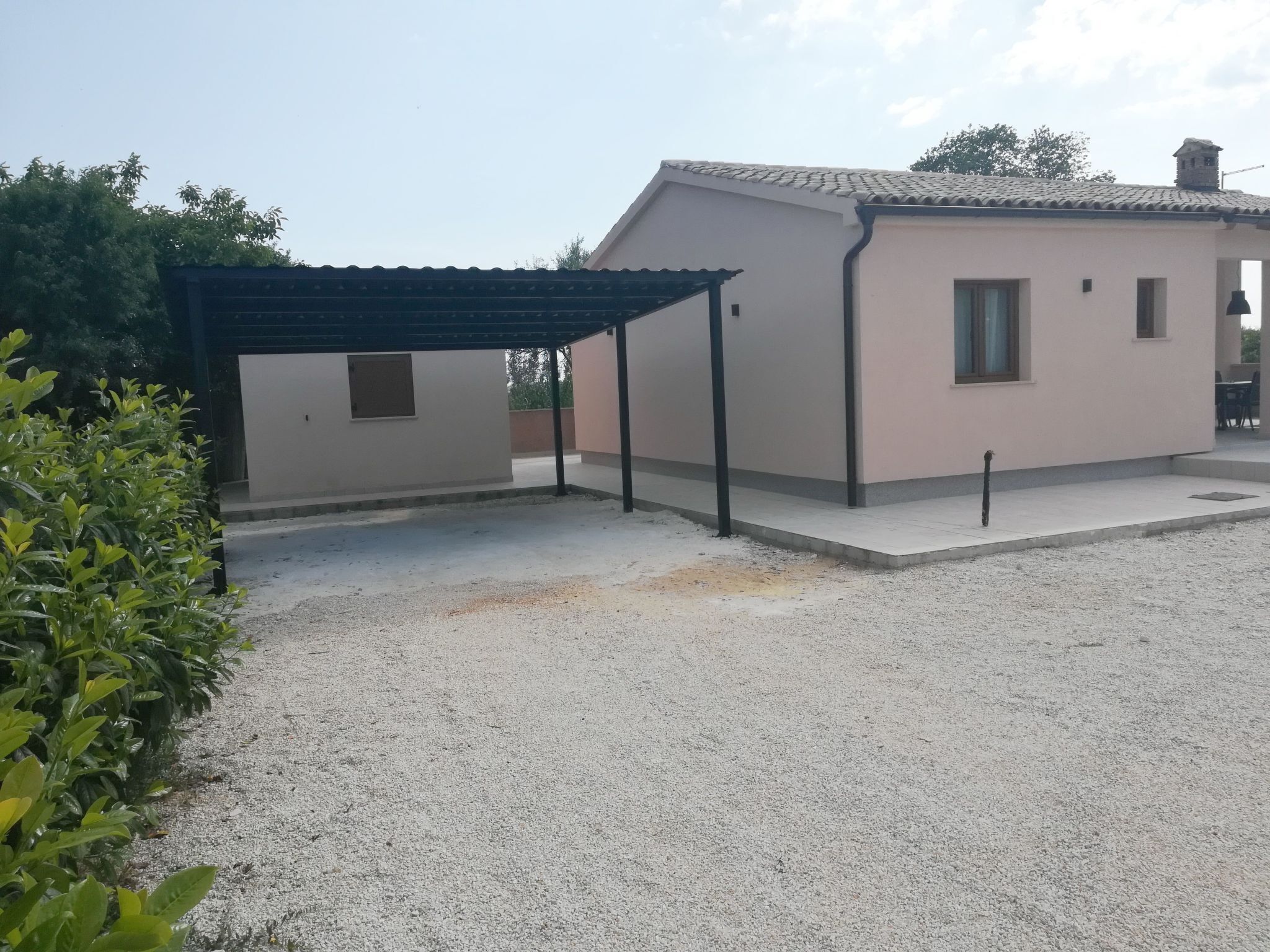 Um edifício com área externa coberta, entrada de cascalho e um pequeno jardim.
