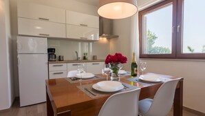 Eine moderne Küche mit weißen Schränken, einem Holztisch gedeckt mit weißen Tellern, Gläsern und einer Champagnerflasche.