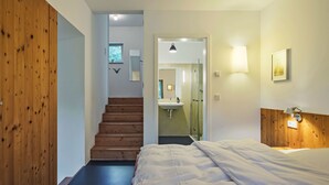 A bedroom with a bed, a wooden wardrobe, a staircase leading to a bathroom, and a small window. - Moderner Holzhausneubau in der Eifel by Interhome (Berlingen)